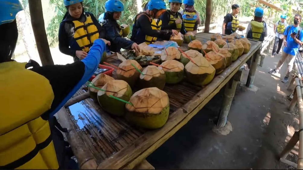 People preparing coconuts with straws on a wooden table. 2