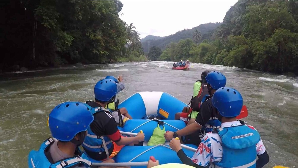 A group of people rafting down a river surrounded by dense greenery. 4