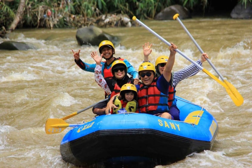 A group of people in a blue inflatable raft with 'SANY' on it, paddling through a river. 1