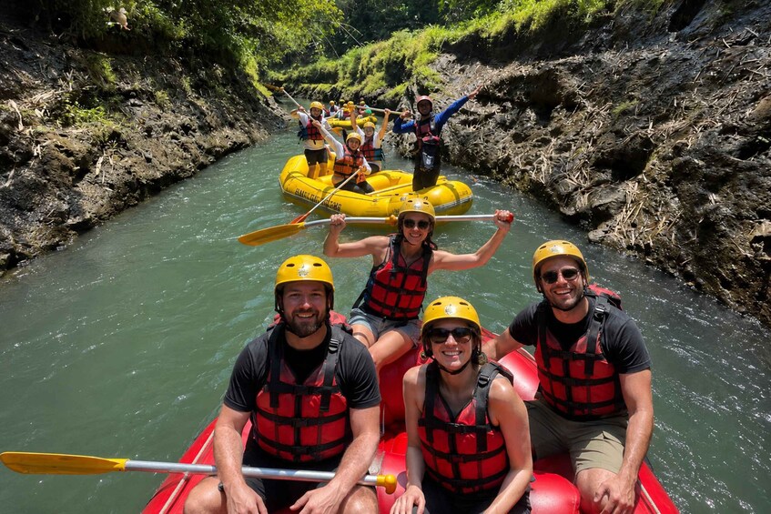 A group of people in a yellow raft on a river surrounded by rocky banks. 1