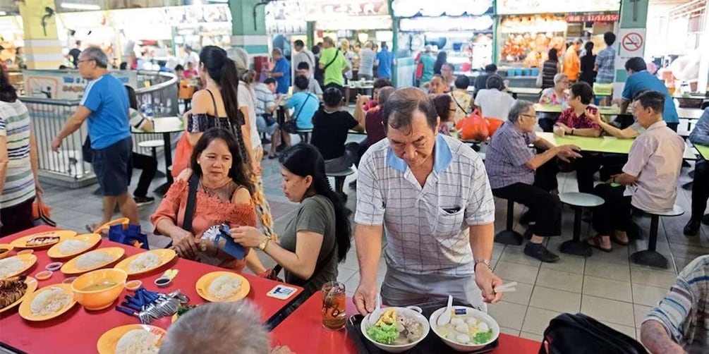 A crowded indoor market with people dining at tables. 2