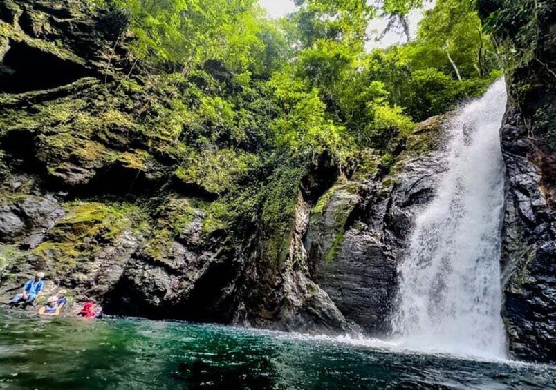 A waterfall cascading into a river surrounded by lush greenery and rocky cliffs. 3