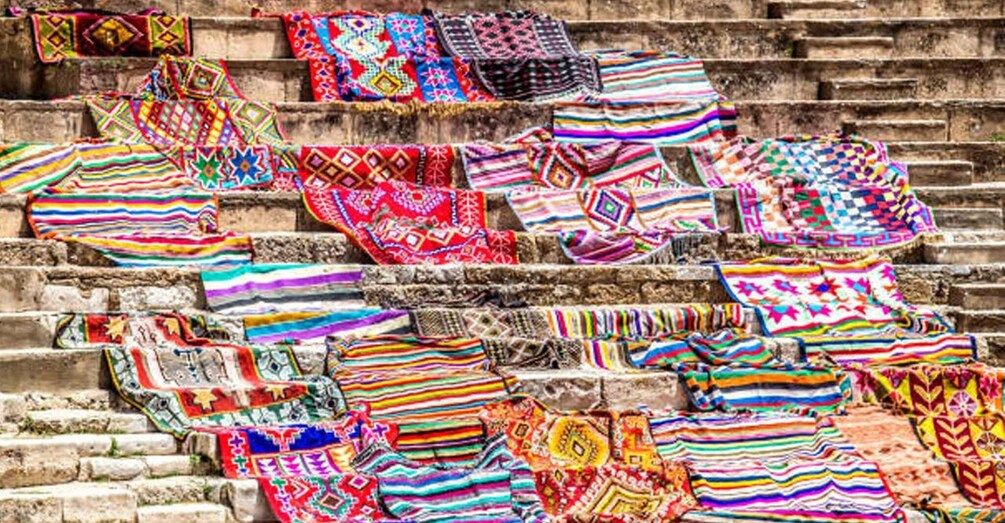 A staircase with colorful, patterned blankets draped over the steps. 4