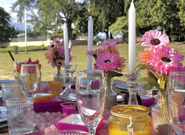 A table set outdoors with pink flowers, candles, and glassware. 5