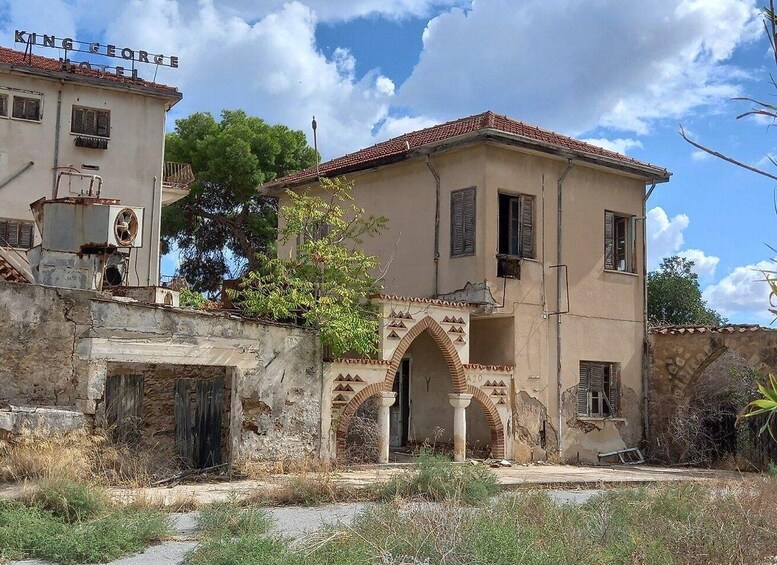An old building with a sign that reads 'King George Hotel,' featuring a red-tiled roof and arched doorways. 5
