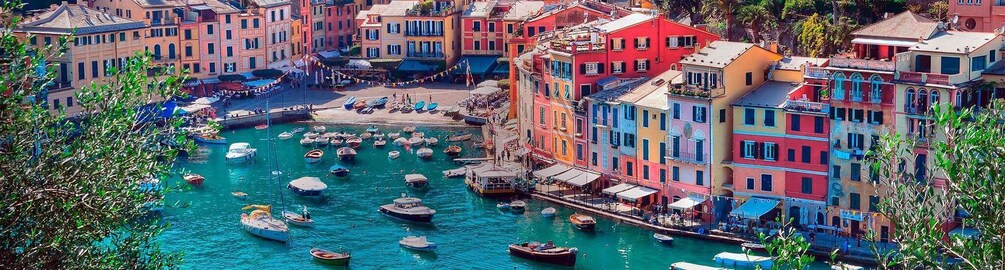 A coastal town with colorful buildings, a marina with boats, and a clear turquoise sea. 1