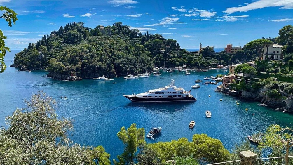 A coastal town with a large yacht anchored in the harbor, surrounded by lush greenery and historic buildings. 3