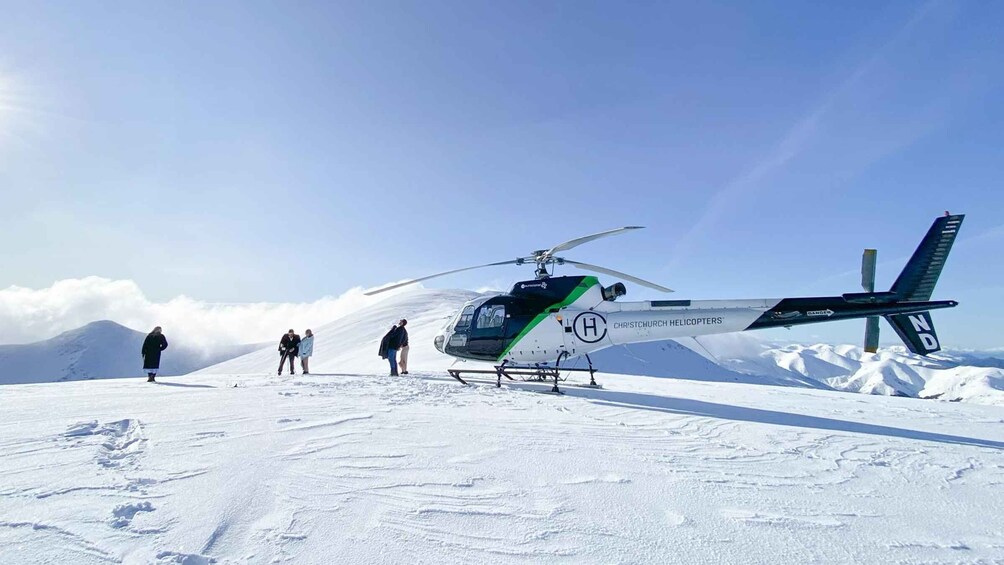 A helicopter on a snowy mountain with people standing nearby. 2