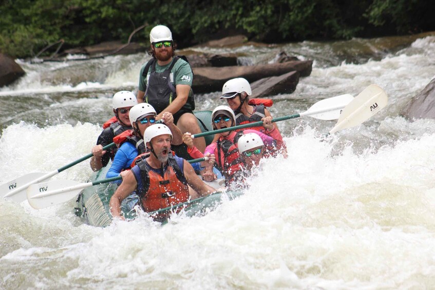 A group of people in a white raft navigating through a river with rapids. 2
