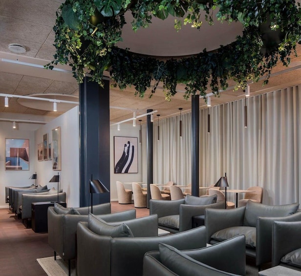 A modern interior with leather chairs, a green plant installation, and abstract art. 2