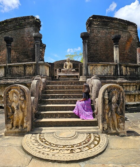 A woman sitting on stone steps with a temple in the background. 2