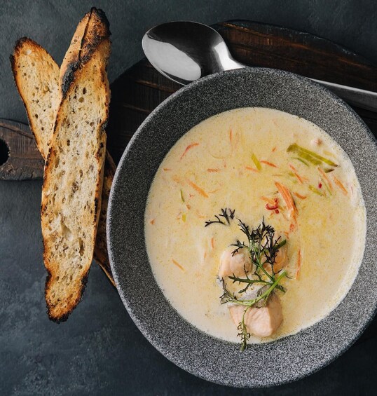 A bowl of creamy soup with vegetables and a garnish, accompanied by toasted bread slices. 2