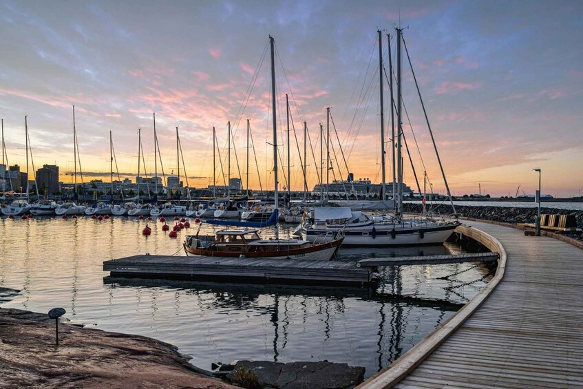 A marina with multiple sailboats docked at wooden piers during sunset. 3