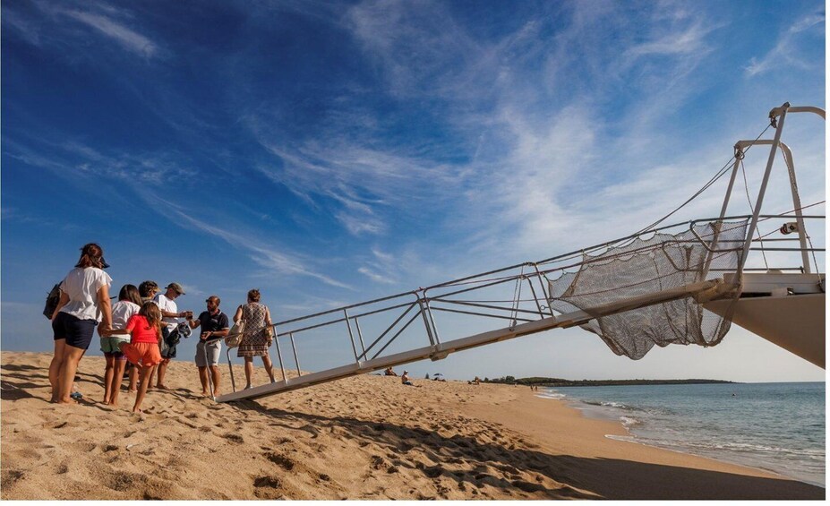 A beach with people standing near a large fishing net structure. 5