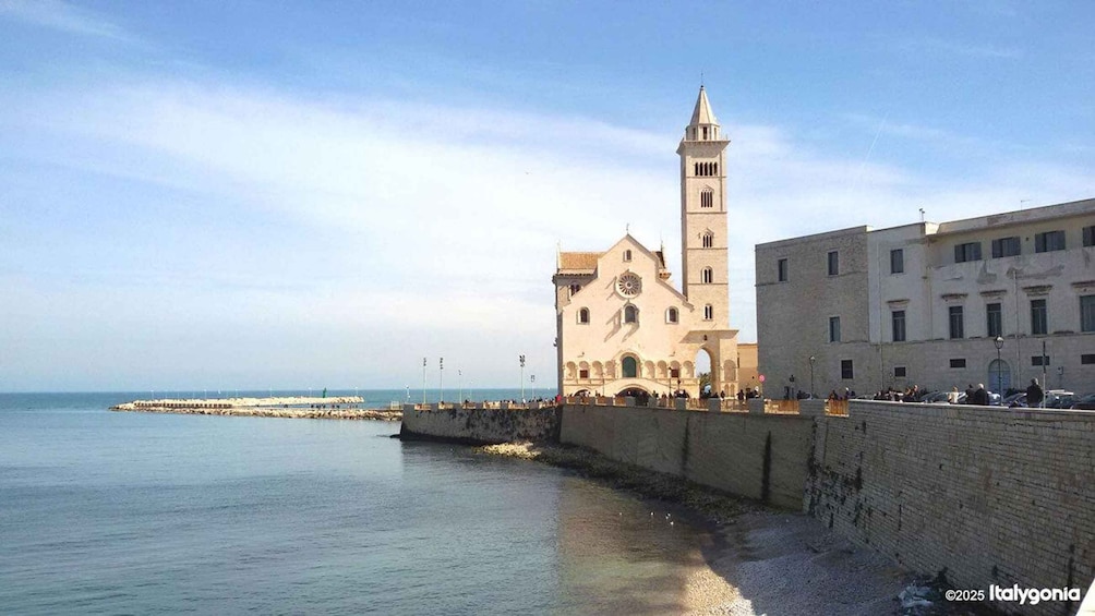 A coastal town with a prominent church featuring a bell tower, a sea wall, and a distant pier. 1