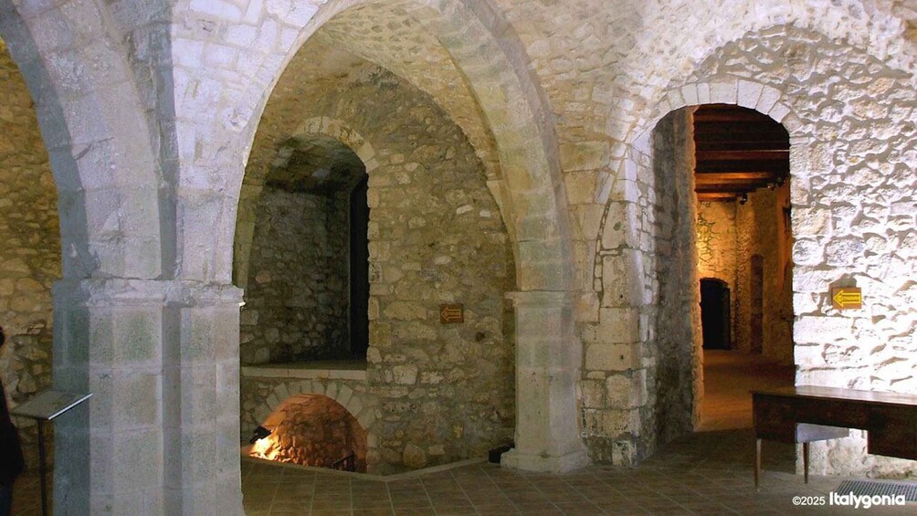 An ancient stone building with arched doorways and a fireplace. 2