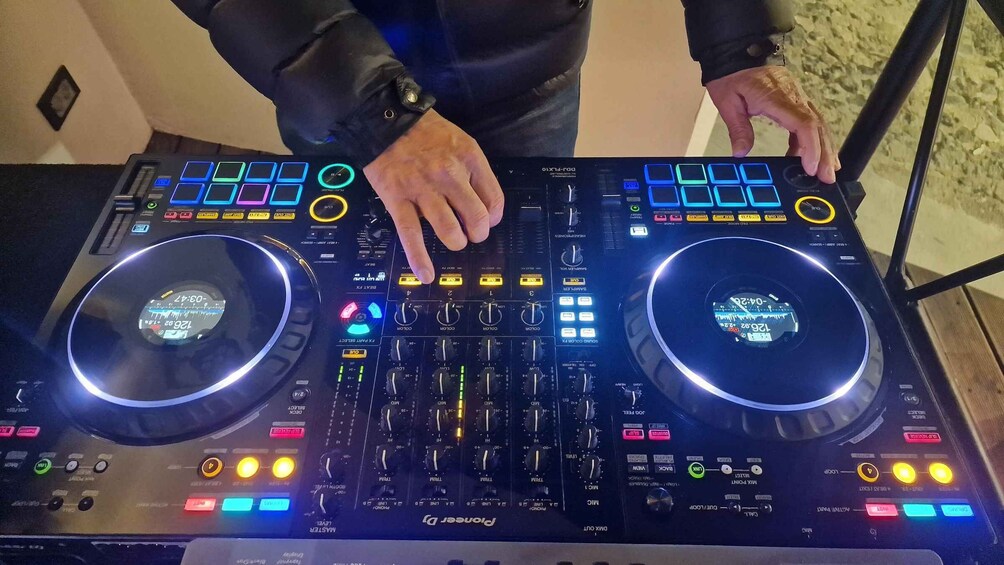 A DJ mixer with two illuminated decks, various knobs, and buttons. 3