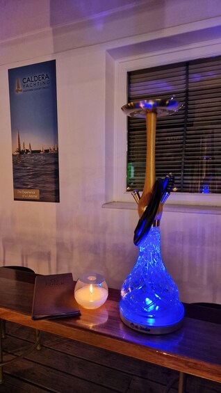A table with a blue-lit lamp, a lit candle, and a poster of sailboats. 4
