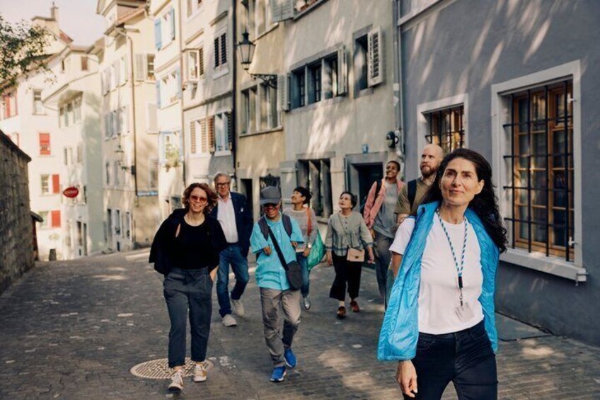 A group of people walking down a narrow street lined with buildings. 1