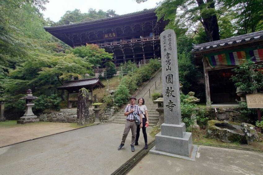 A traditional Japanese temple with a stone monument and a staircase leading to a wooden building. 5