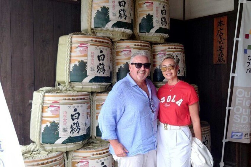 A man and a woman standing in front of large stacks of packaged goods with Japanese text. 4