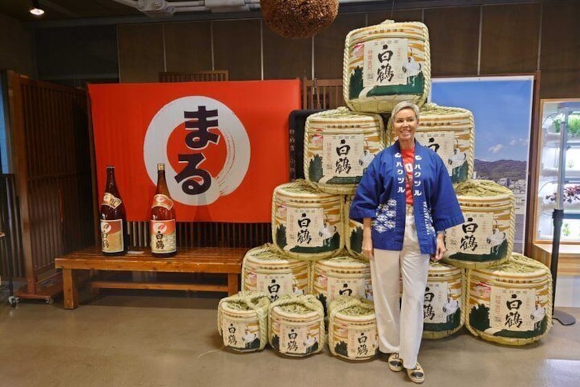 A person standing in front of a display of large, round, woven containers with Japanese characters, and a red sign with a white circle and Japanese characters. 3