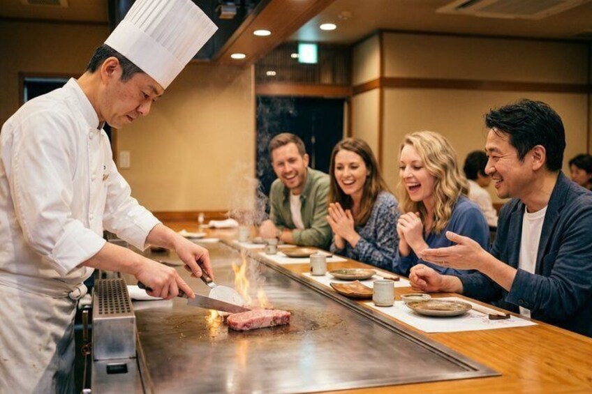 A chef cooking on a grill with a group of diners watching. 1