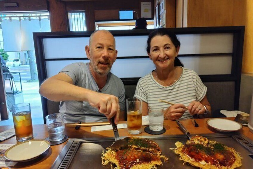 Two people dining at a restaurant with a large grilled dish in front of them. 4