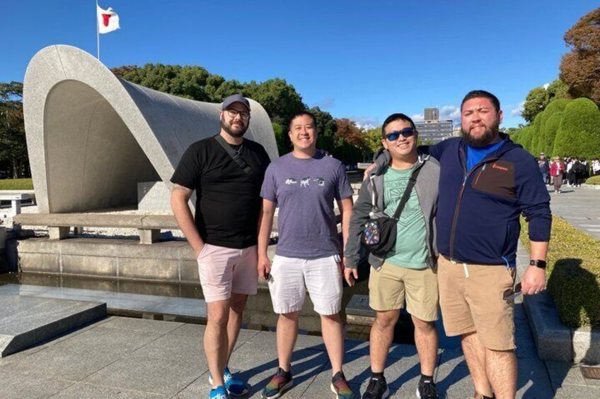 Four people standing in front of a modern sculpture with a flag in the background. 5