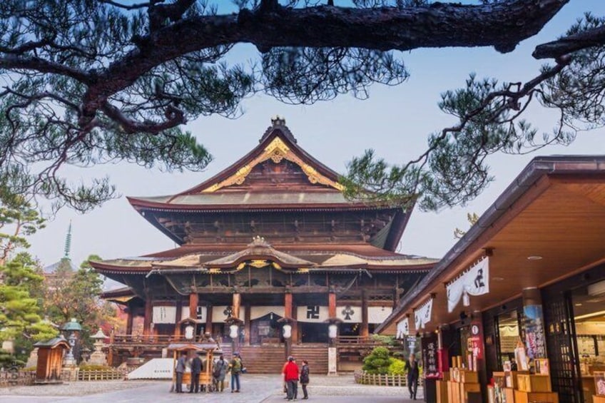 A traditional Japanese building with a prominent roof and wooden structure, surrounded by trees and a clear sky. 2