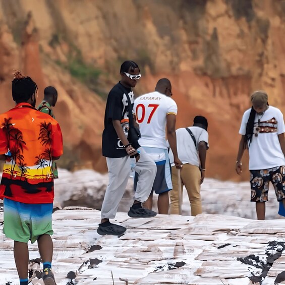 A group of people standing on a rocky surface with a desert landscape in the background. 3