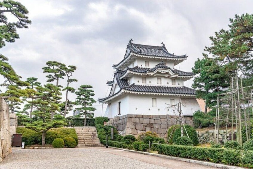 A traditional Japanese castle with multiple tiers, surrounded by well-maintained gardens and trees. 5