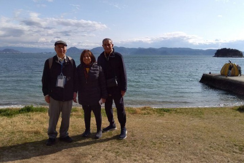 Three people standing by a lake with mountains in the background. 3