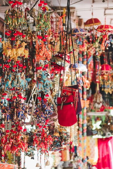 A variety of colorful hanging ornaments and a red bag in a market. 2