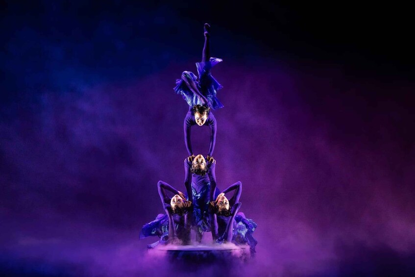 A person in a blue costume performing a balancing act on a platform. 1