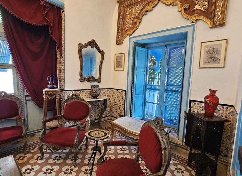 A room with ornate furniture, a blue door, and patterned tiles. 4