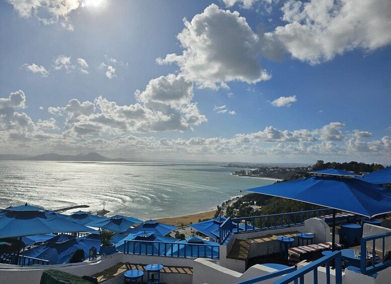 A coastal view with a beach, ocean, and blue umbrellas. 2