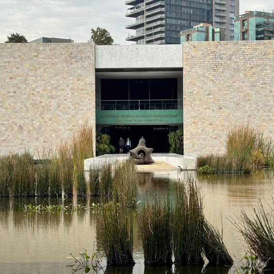 A building with a sign reading 'INVENTIVO IN ITALIA EN MEXICO TENOCHTITLAN' surrounded by water and reeds. 3