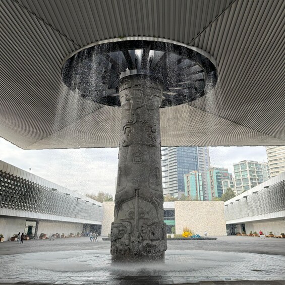 A water fountain with a large, ornate column and a wide, flat canopy overhead. 1