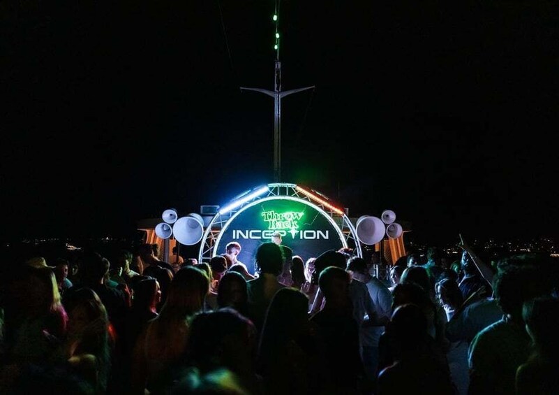 A crowd at a nighttime event with a stage featuring a 'Throwback Inception' sign. 2