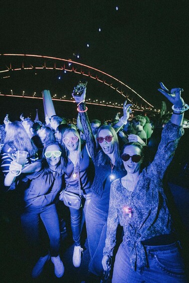 A group of people at a nighttime outdoor event with string lights overhead. 3