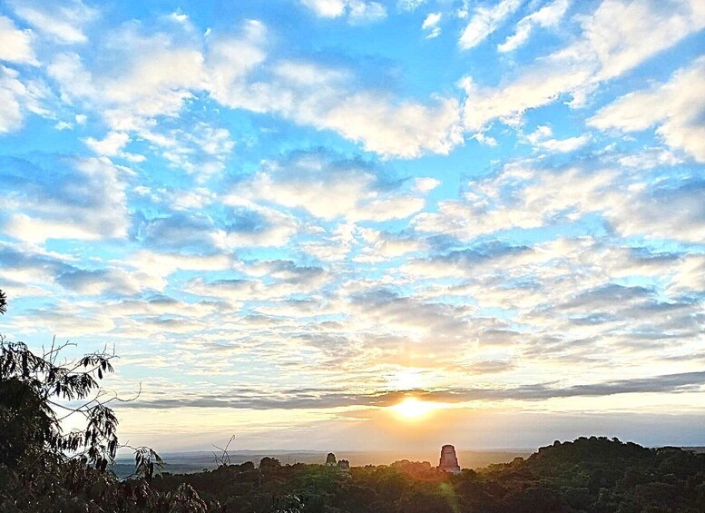 A sunset over a mountainous landscape with scattered clouds and a prominent rock formation in the distance. 5