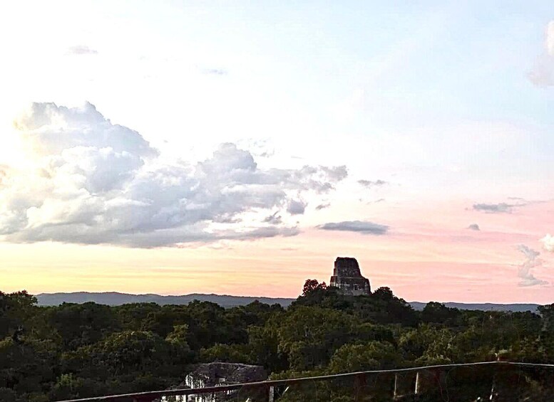 A sunset over a landscape with a prominent hilltop structure. 1
