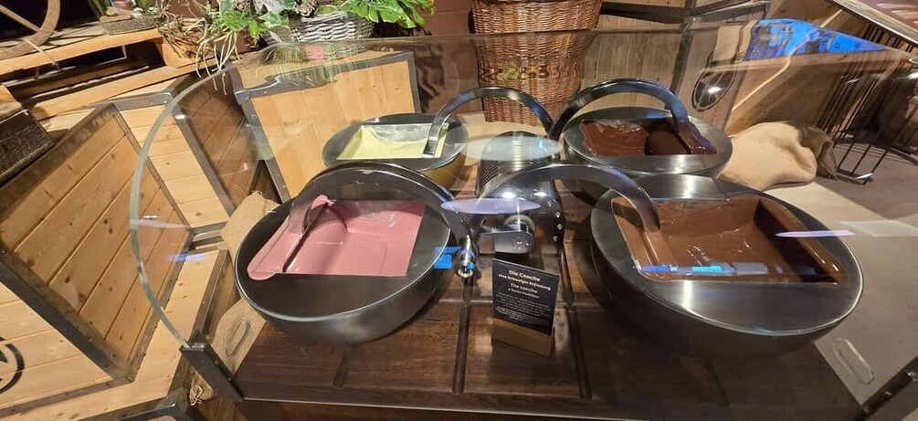 A display of black bowls with lids on a wooden table, surrounded by baskets and a wicker basket. 1
