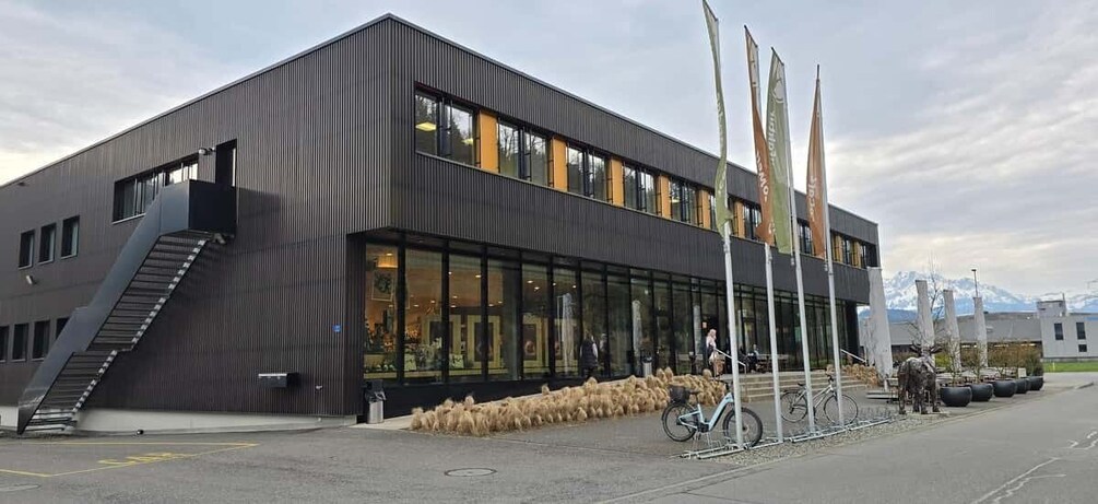 A modern building with a staircase, large windows, and flags. 3