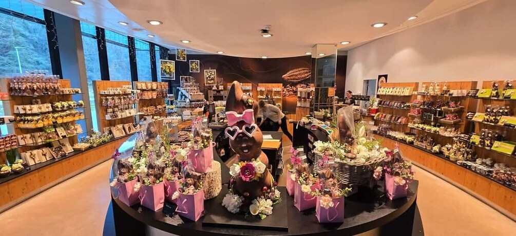A store with shelves of chocolates and flowers, and a large chocolate bunny with a bow. 2