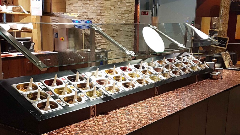 A buffet with multiple food dispensers, a stone wall, and a counter with a tiled backsplash. 4