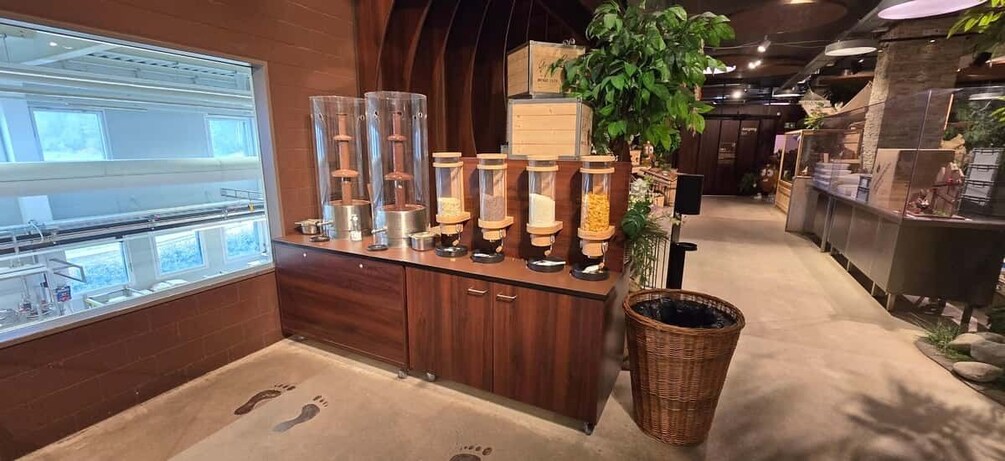 A café with a wooden counter, a plant, and a trash bin. 5