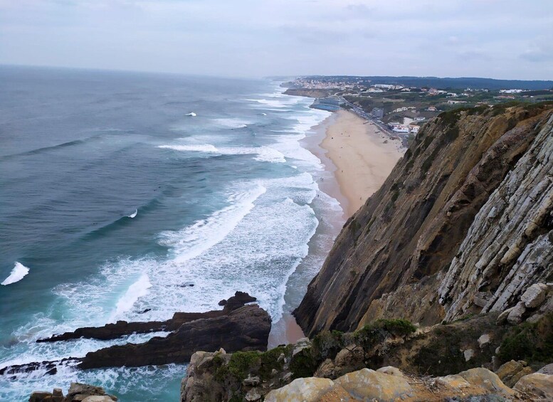 A coastal landscape with a beach, ocean waves, and a cliff. 5