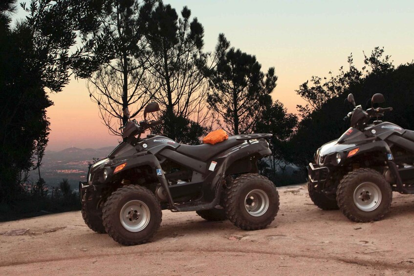 Two ATVs parked on a dirt path with a sunset in the background. 4